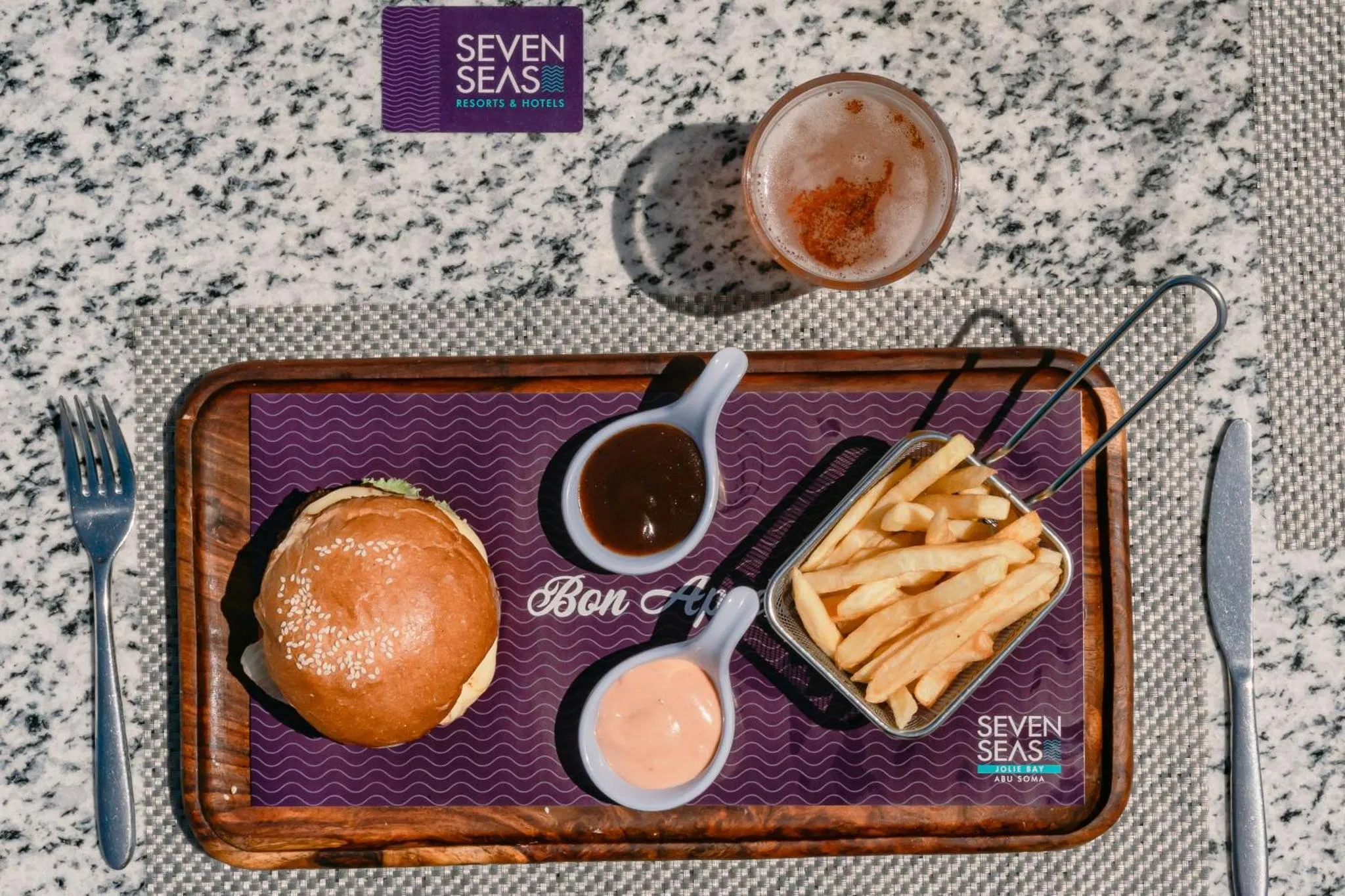 Assiette de repas avec un burger, des frites et des sauces.