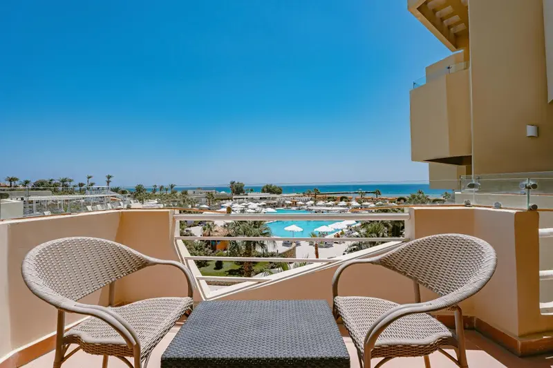 Deux fauteuils en osier invitent à la détente sur une terrasse ensoleillée avec vue sur la mer.