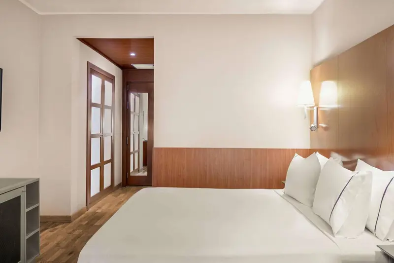 Une chambre lumineuse avec un grand lit et un accès à une autre pièce.