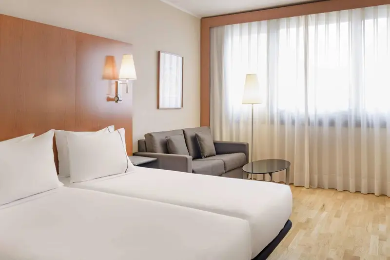 Une chambre lumineuse avec un lit et un coin salon.