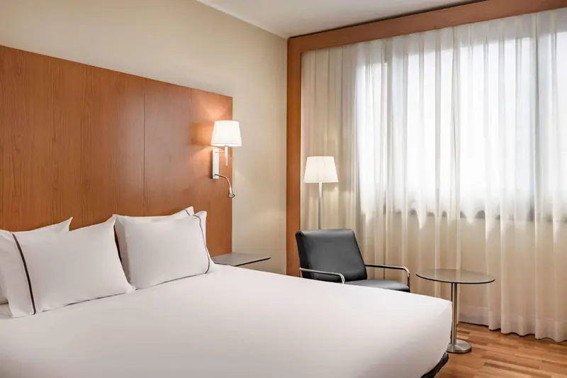 Une chambre lumineuse avec un grand lit et un fauteuil.