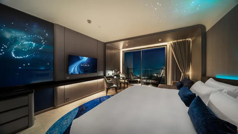 Chambre moderne avec un grand lit et une vue sur la mer nocturne.