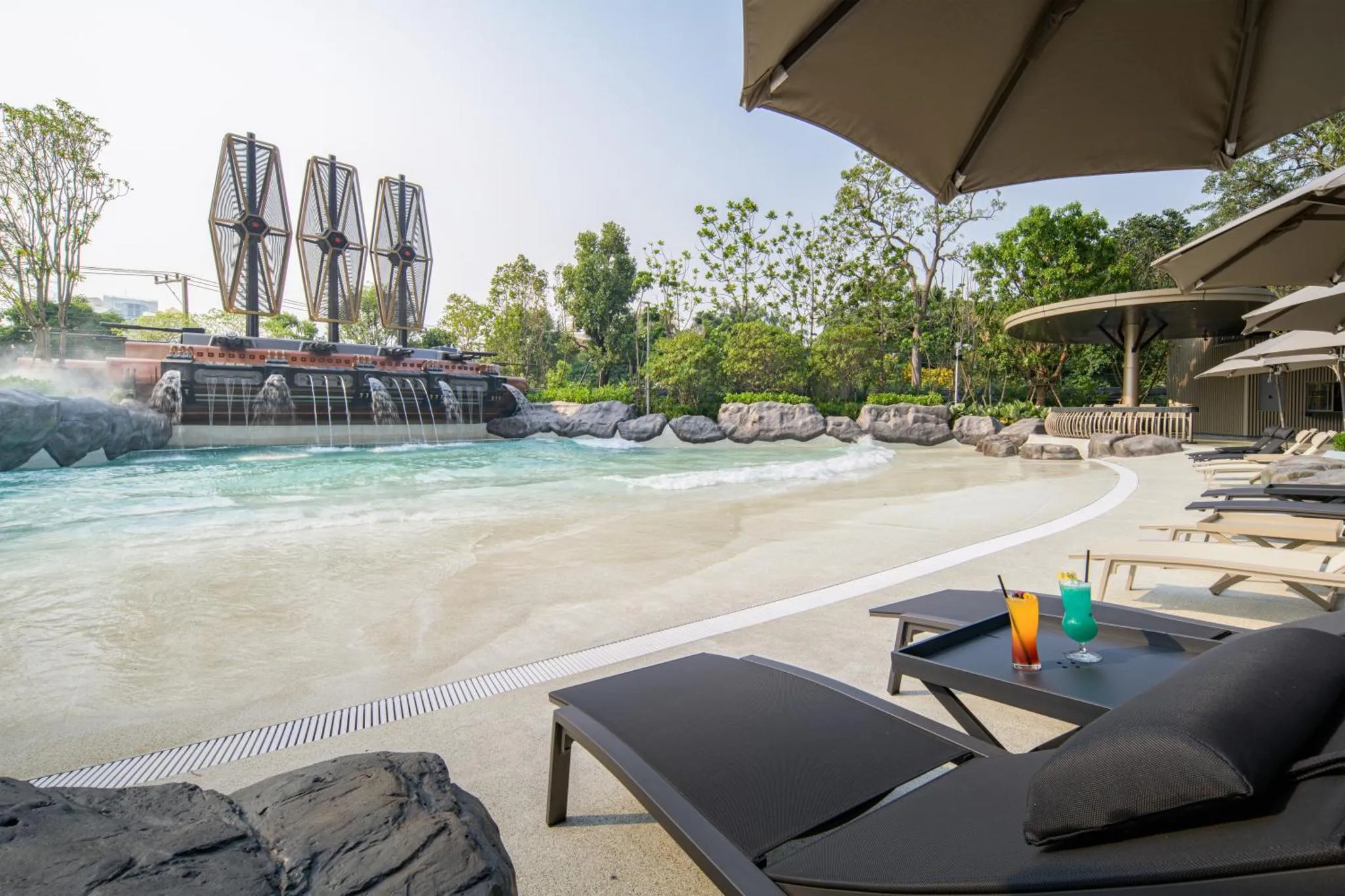 Transats et table basse avec boissons sur une plage artificielle.
