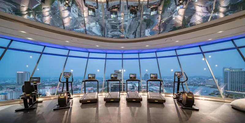 Une salle de sport lumineuse offre une vue panoramique sur la ville.