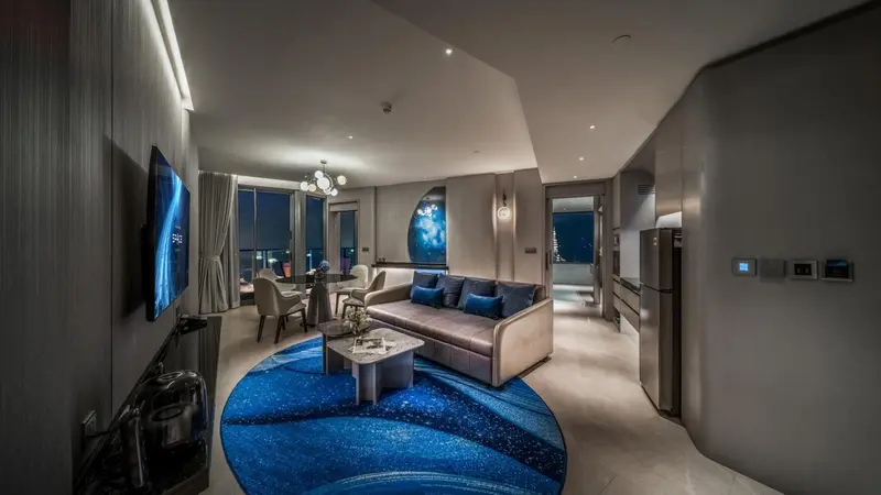 Un salon moderne avec canapé, table basse et télévision face à une grande baie vitrée.