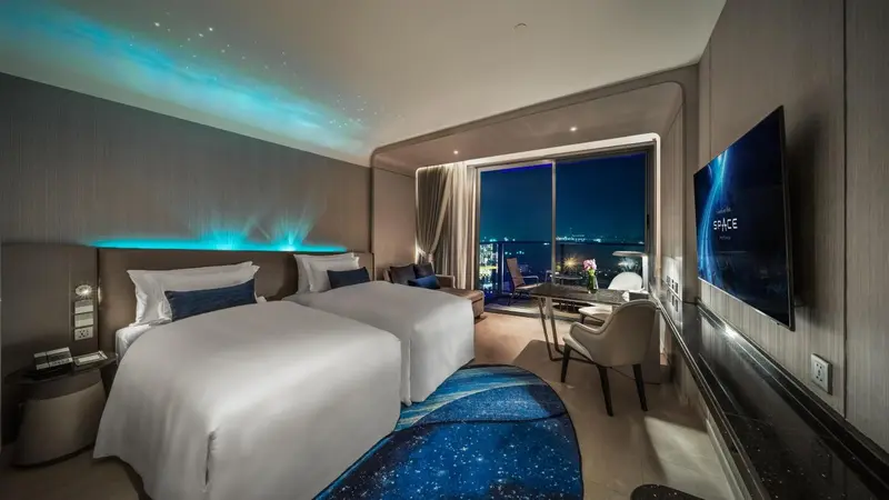 Chambre moderne avec deux lits simples et vue sur la ville.