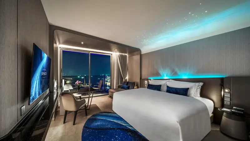 Une chambre moderne avec un grand lit et une vue nocturne sur la ville.