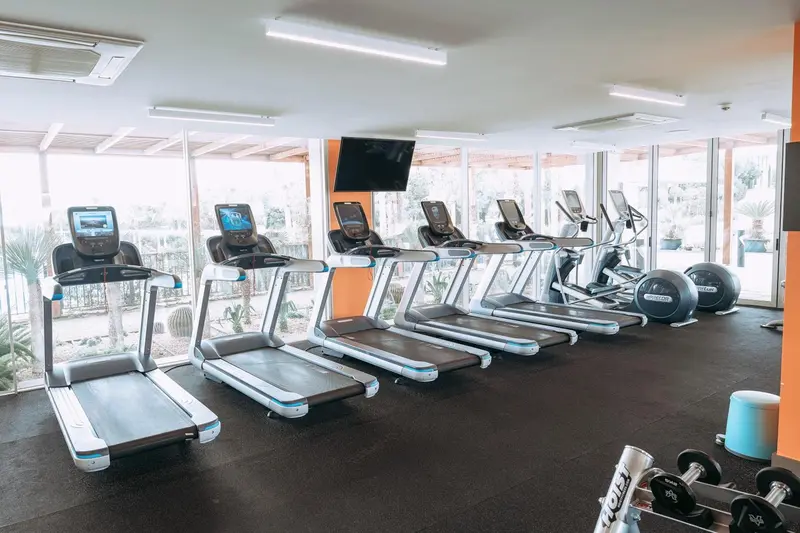 Une salle de sport lumineuse avec des équipements de cardio et de musculation.