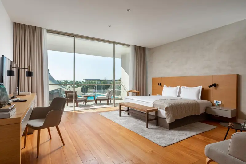 Une chambre lumineuse avec un grand lit et un accès à une terrasse avec vue sur la mer.
