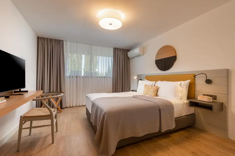 Une chambre lumineuse avec un lit double et un bureau.