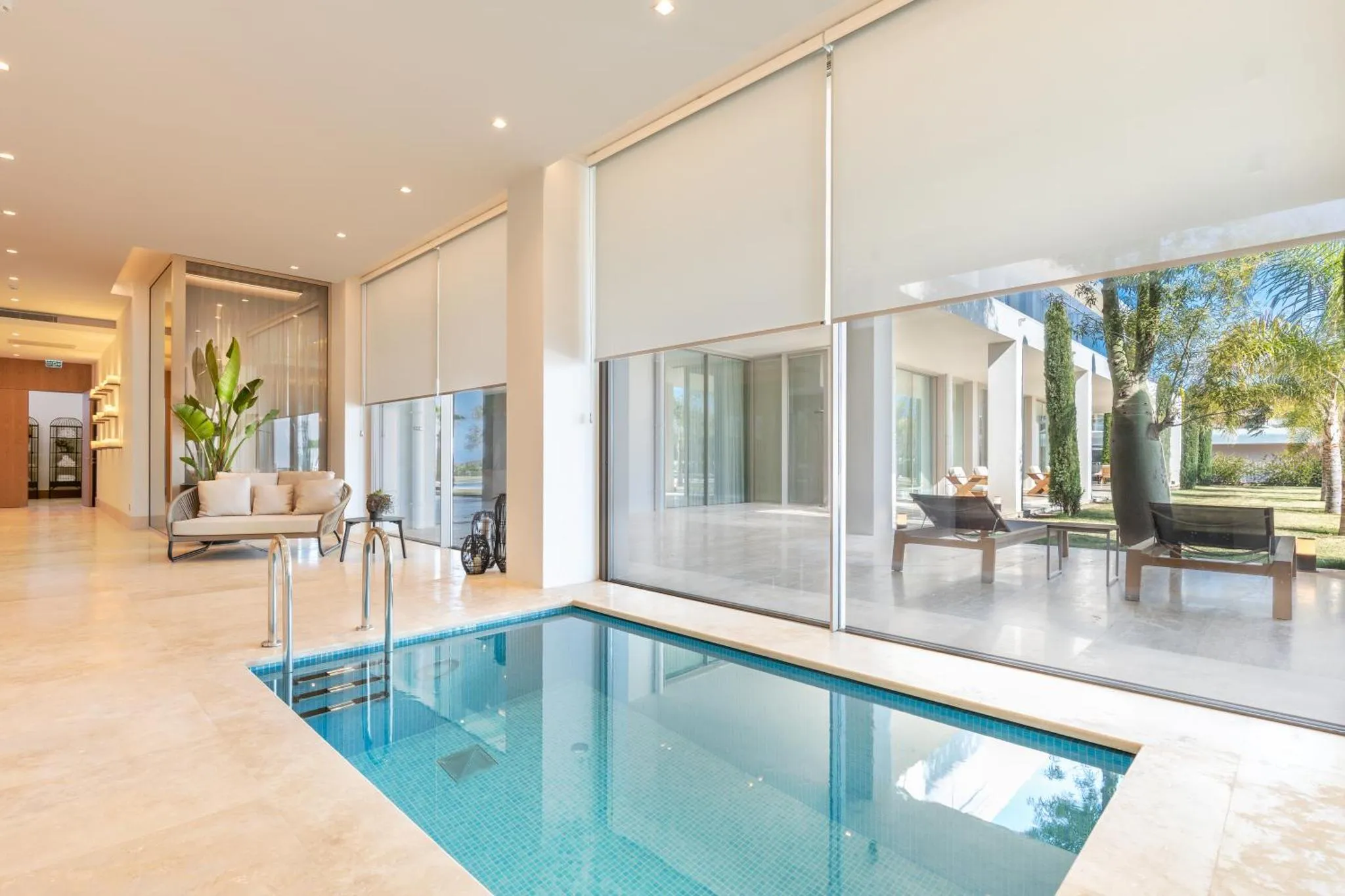 Espace de détente intérieur avec piscine et vue sur un jardin luxuriant.