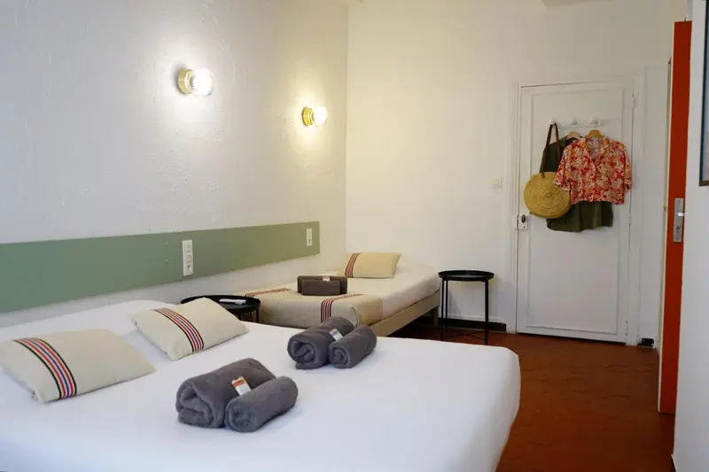Une chambre lumineuse avec deux lits simples et une décoration sobre.