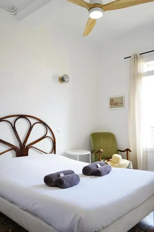 Une chambre lumineuse avec un lit recouvert d'une courtepointe blanche et d'oreillers.