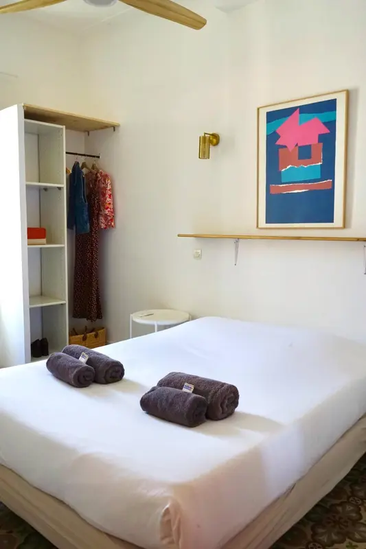 Une chambre lumineuse avec un lit recouvert de draps blancs et des serviettes.