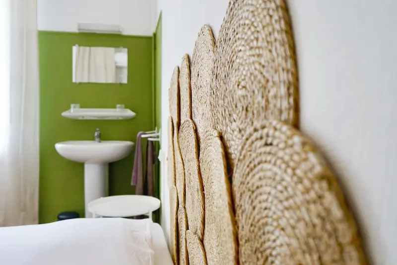 Une chambre lumineuse avec un lavabo et une décoration murale en fibres naturelles.