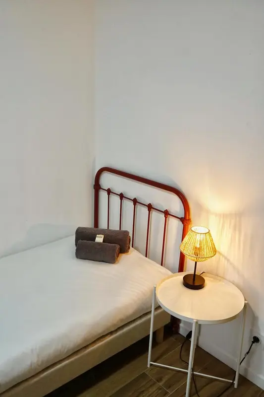 Un lit simple avec une lampe de chevet et des serviettes pliées.