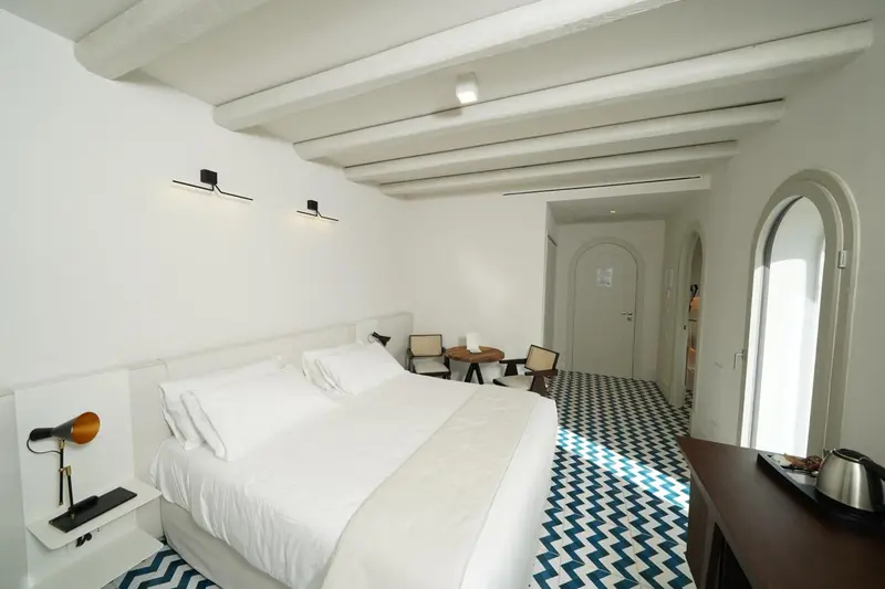 Une chambre lumineuse avec un grand lit et un sol carrelé.