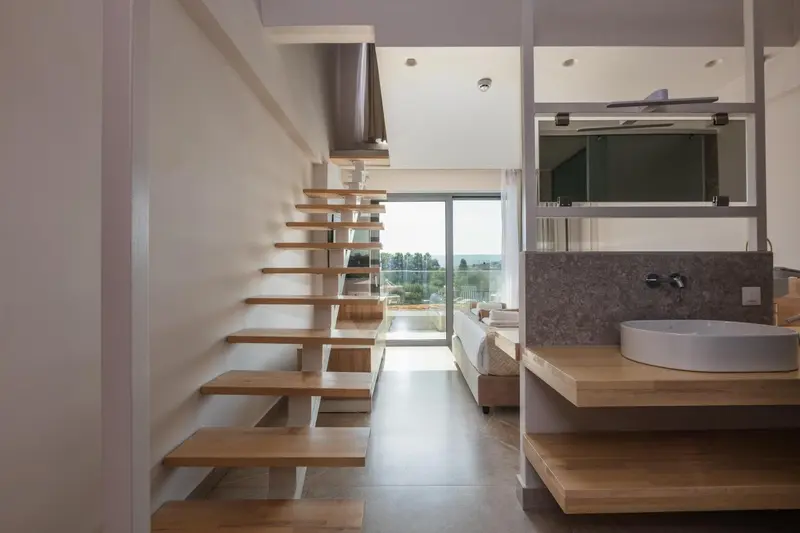 Une salle de bain moderne s'ouvre sur un espace de vie lumineux avec un escalier en bois.