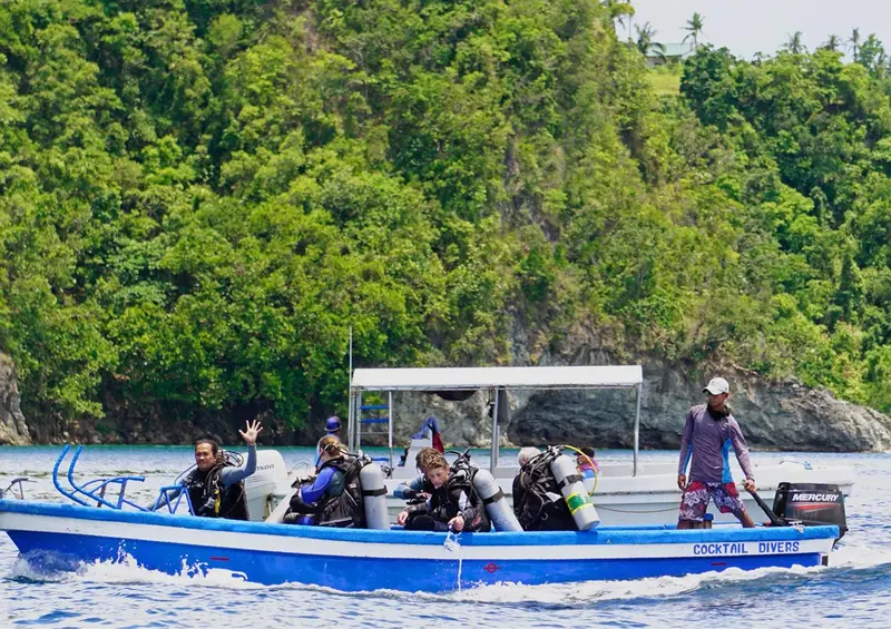 Un bateau bleu navigue sur une eau turquoise, avec des passagers à bord.