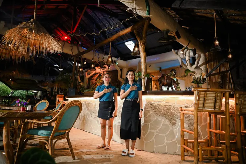 Deux employées souriantes se tiennent derrière un comptoir dans un espace ouvert et décoré.