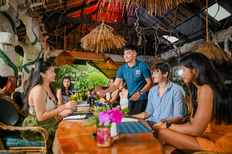 Des clients sont servis à une table dans un restaurant en plein air.