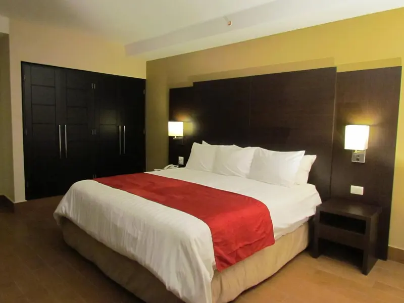 Une chambre avec un grand lit recouvert d'une couette blanche et d'une couverture rouge.