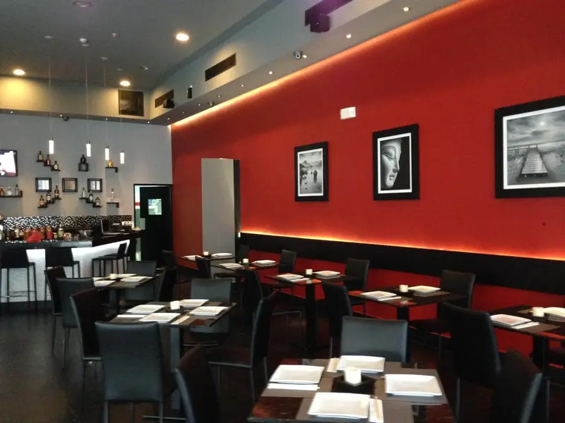 Une salle de restaurant moderne avec des tables dressées et un éclairage tamisé.