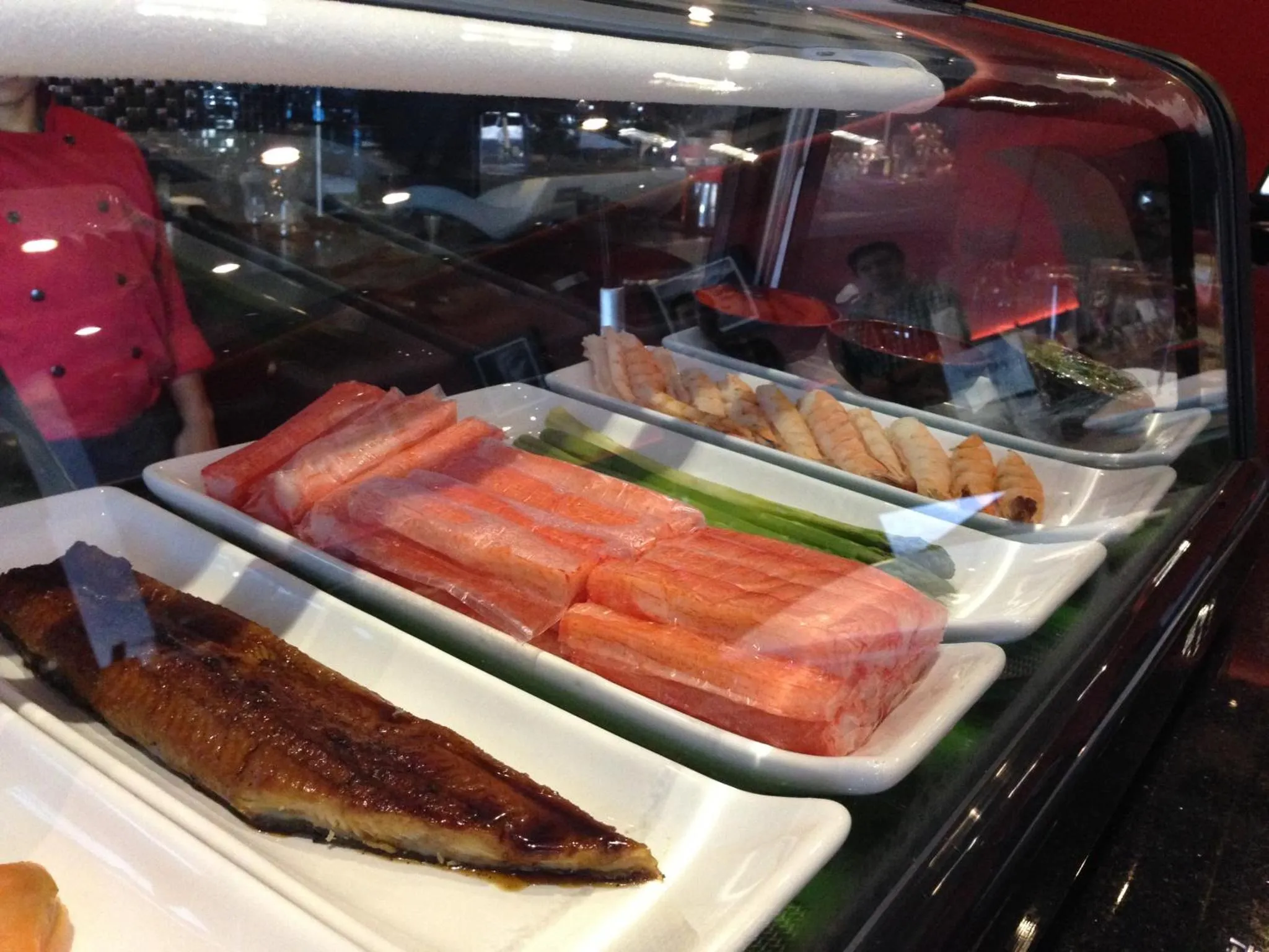 Présentation de sushis et de poisson cru sur un comptoir réfrigéré.