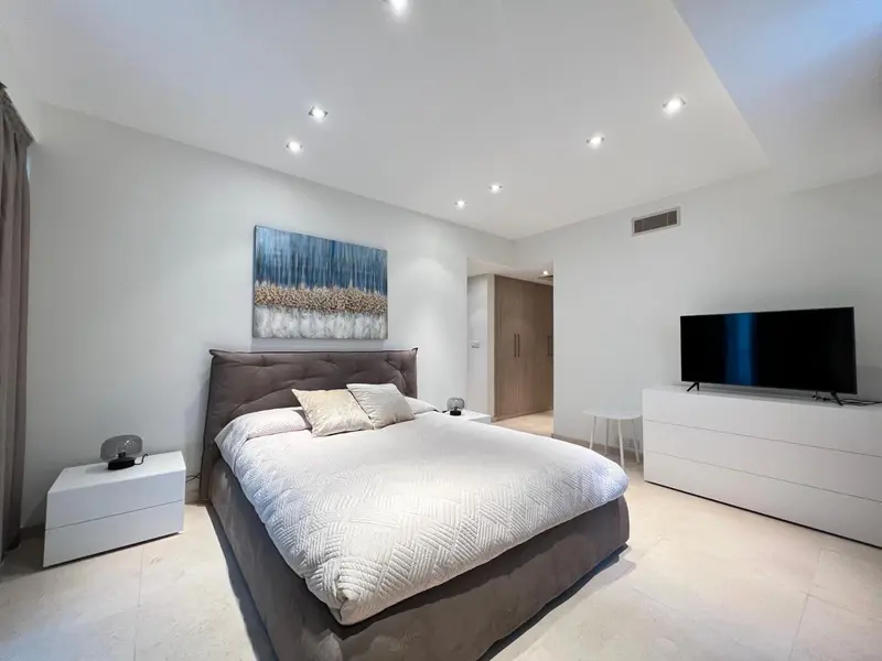 Une chambre moderne avec un grand lit et une décoration sobre.