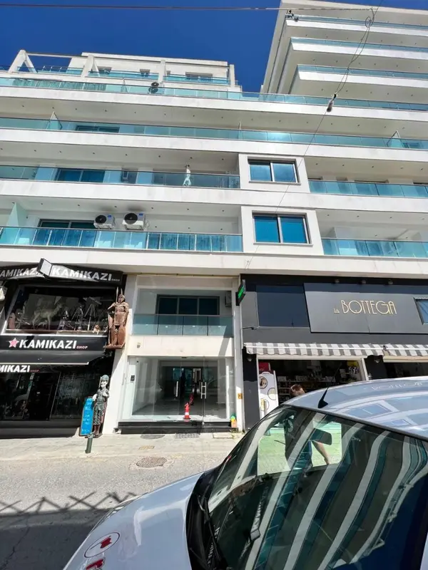 Façade d'un bâtiment avec des commerces au rez-de-chaussée et des balcons aux étages.