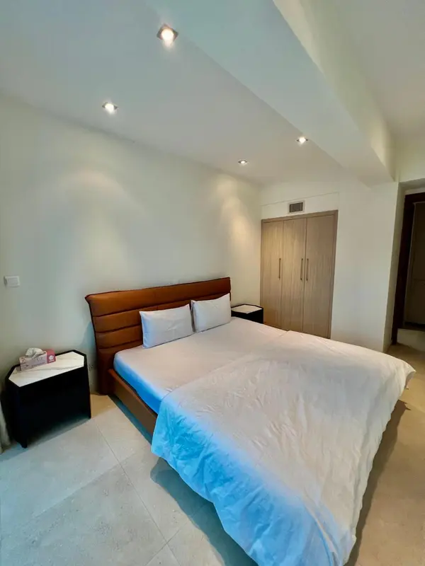 Une chambre lumineuse avec un grand lit recouvert d'une courtepointe blanche.