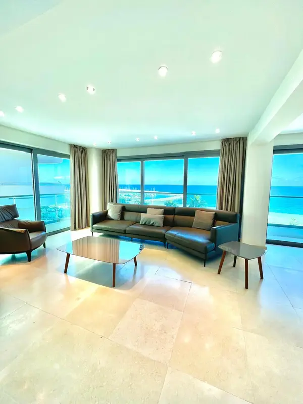 Un salon lumineux avec un canapé d'angle et une vue sur la mer.