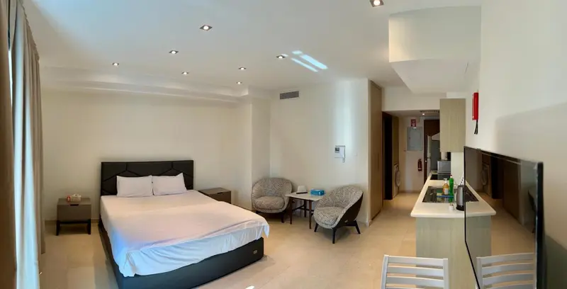 Une chambre lumineuse avec un lit double et un coin salon.