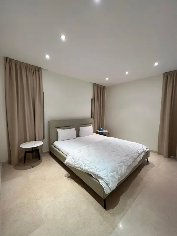 Une chambre lumineuse avec un grand lit recouvert d'une couette blanche.