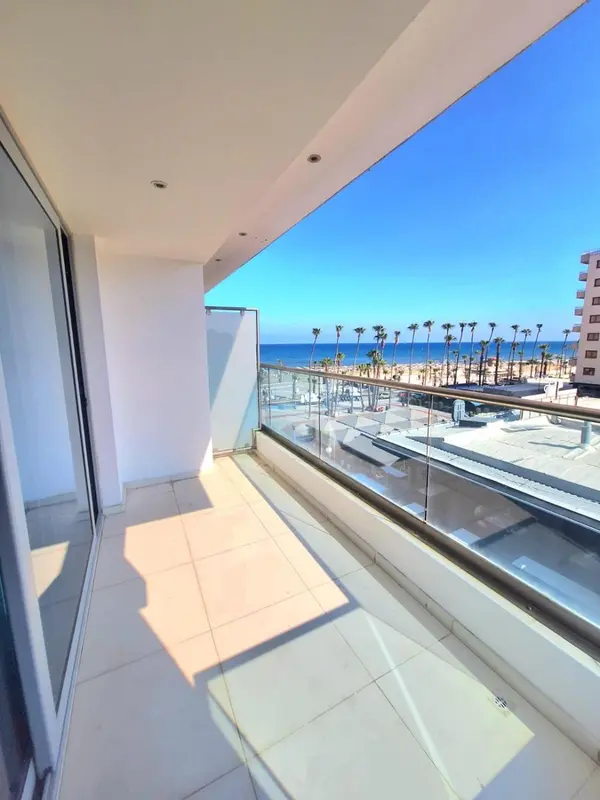 Balcon carrelé avec vue sur la mer et la plage.