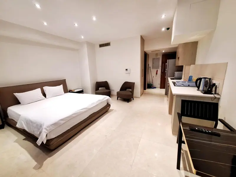 Une chambre lumineuse avec un lit double et une kitchenette.