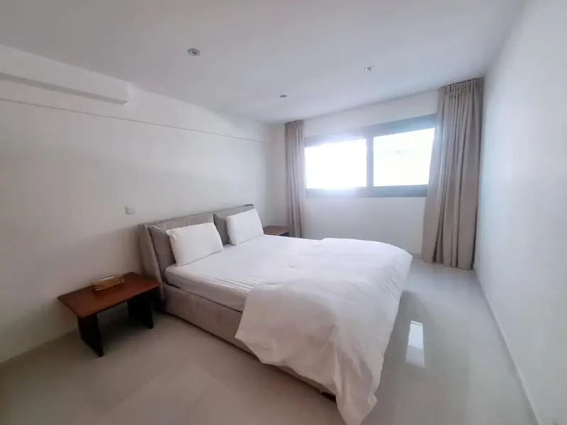Une chambre lumineuse avec un grand lit recouvert de draps blancs.
