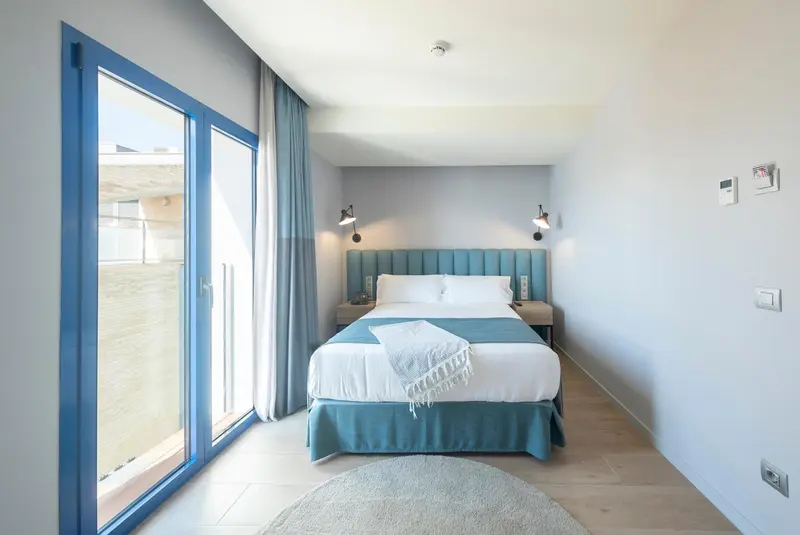 Une chambre lumineuse avec un grand lit et un accès à un balcon.
