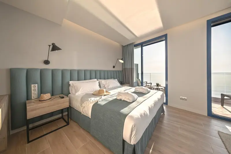 Une chambre lumineuse avec un grand lit et un accès à une terrasse.