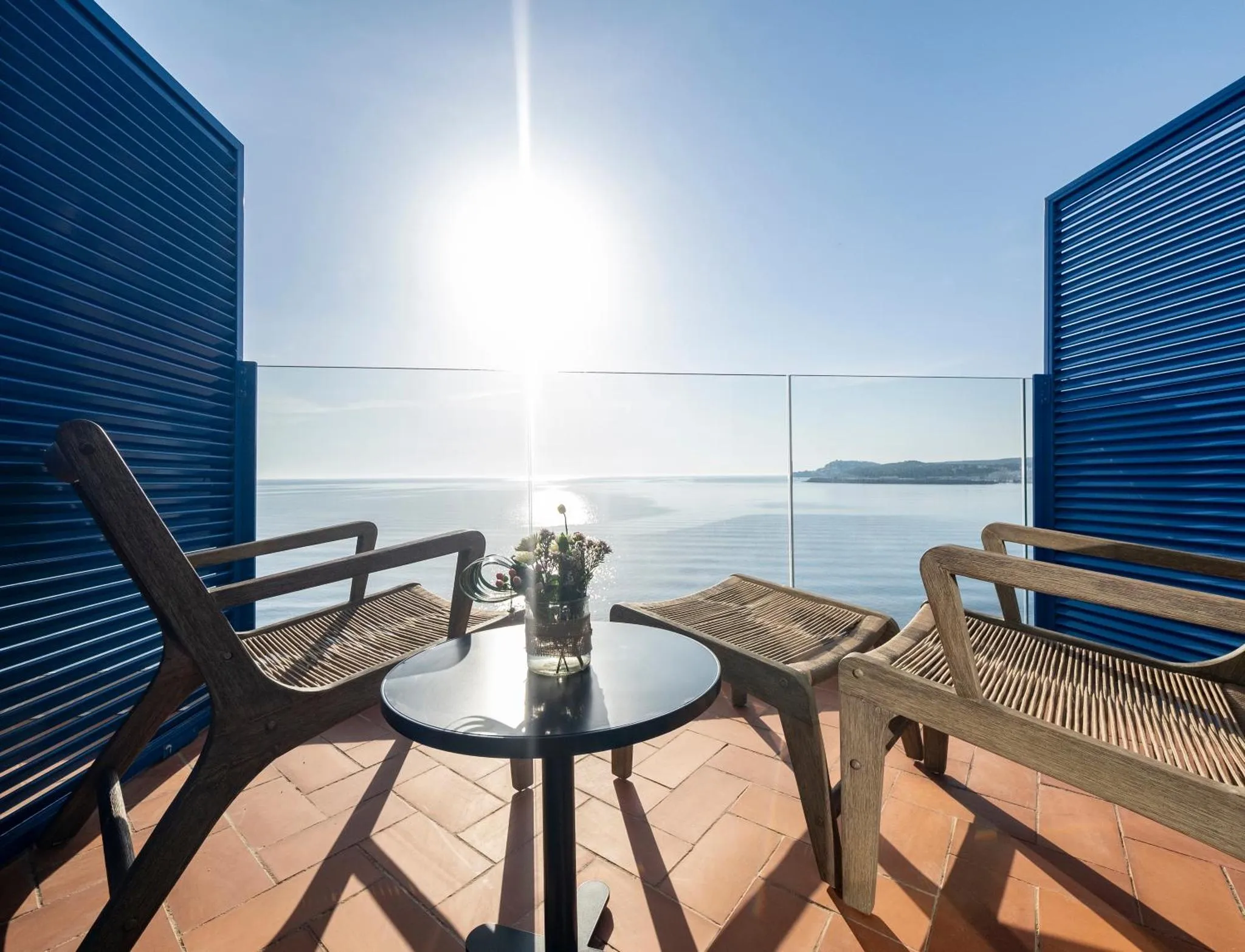 Terrasse avec mobilier en rotin donnant sur la mer.