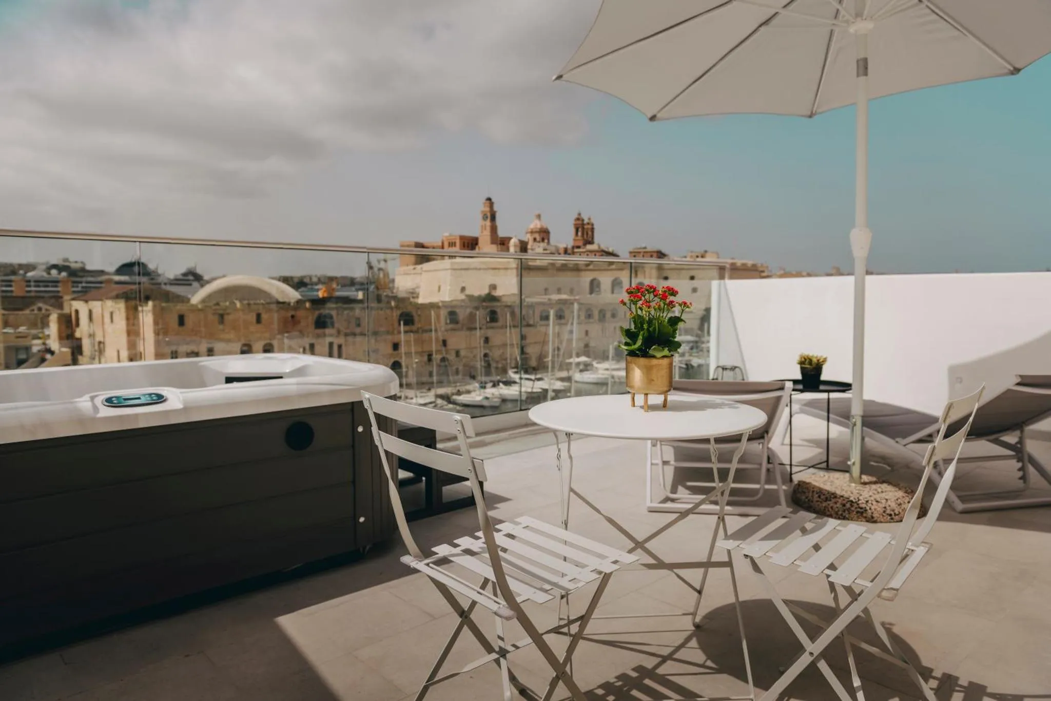 Terrasse aménagée avec jacuzzi et mobilier de jardin offrant une vue sur la ville.