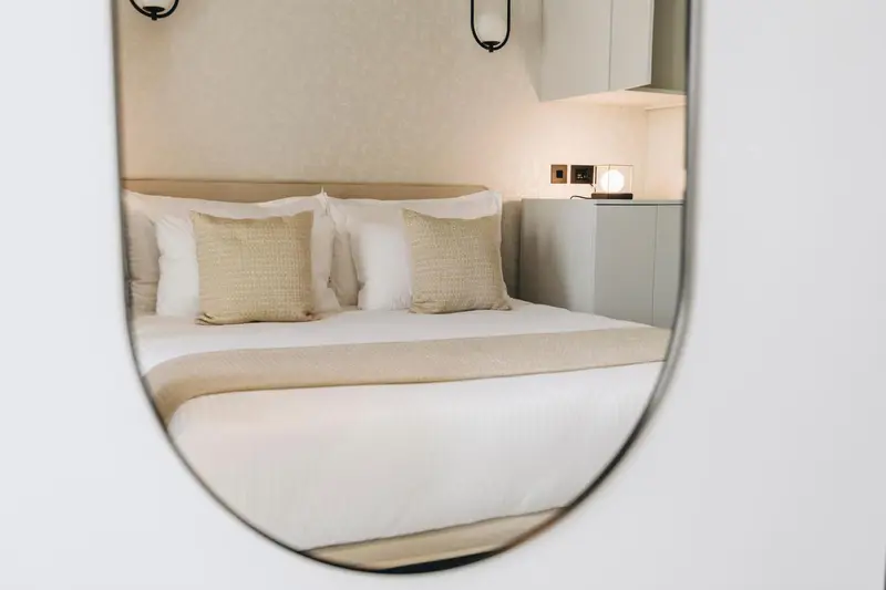 Lit double avec oreillers et linge blanc dans une chambre lumineuse.