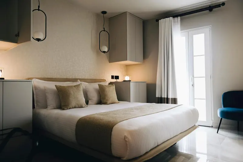 Une chambre lumineuse avec un grand lit et une porte-fenêtre.