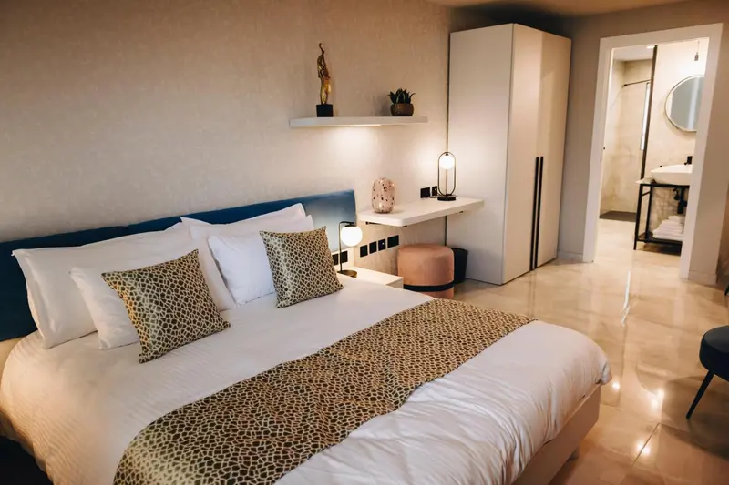 Une chambre lumineuse avec un grand lit recouvert d'une courtepointe.
