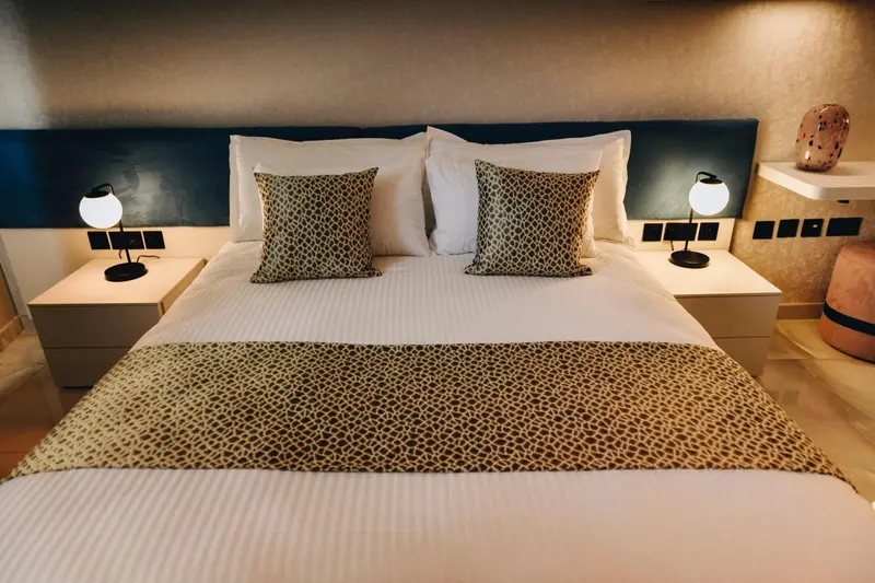 Un lit double est dispose dans une chambre decorée de coussins et d'une couverture à motifs.