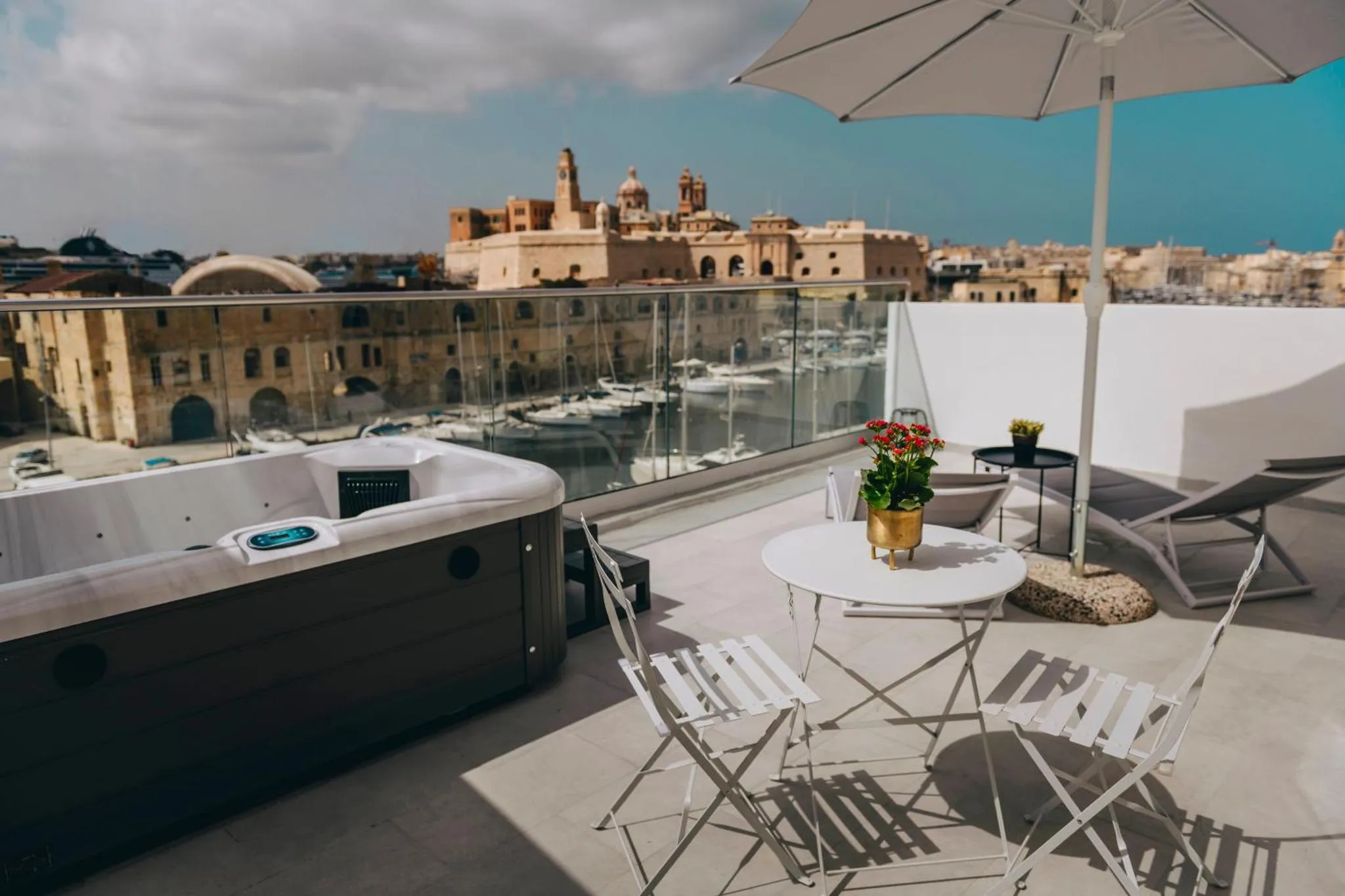 Terrasse aménagée avec jacuzzi et mobilier de jardin offrant une vue sur la ville et le port.