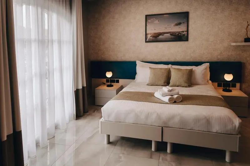 Une chambre lumineuse avec un grand lit et des rideaux blancs.