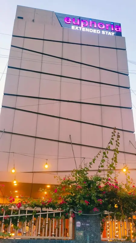 Facade d'un immeuble avec une végétation luxuriante en contrebas.