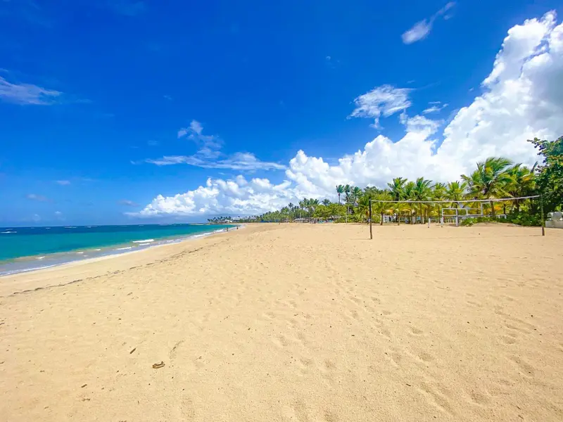 Une plage de sable fin bordée d'eau turquoise sous un ciel bleu nuageux.