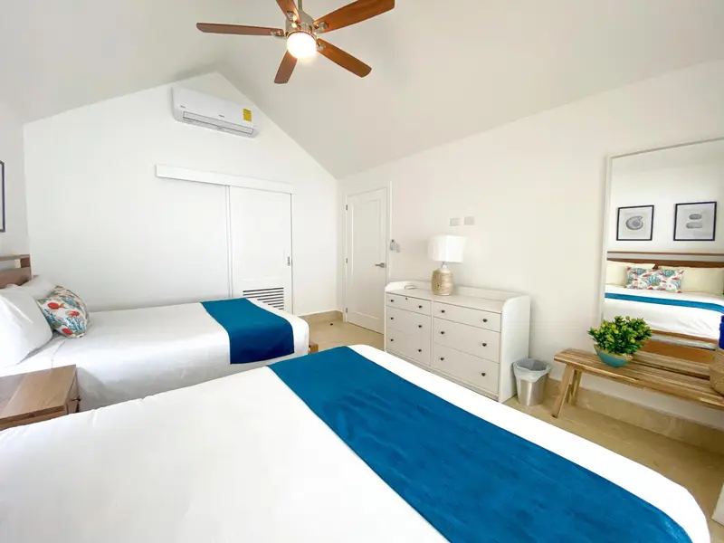 Chambre lumineuse avec deux lits simples et une commode.